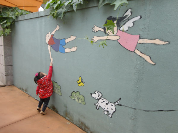 골목 벽면에 그려진 아기자기한 동심 세계의 그림과 순수한 아이의 만남